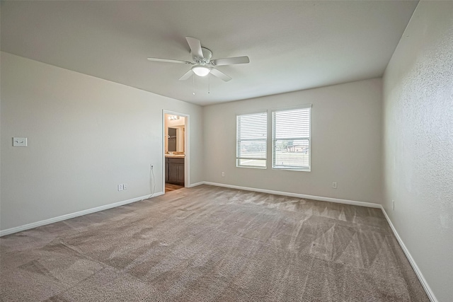 carpeted spare room featuring ceiling fan and baseboards