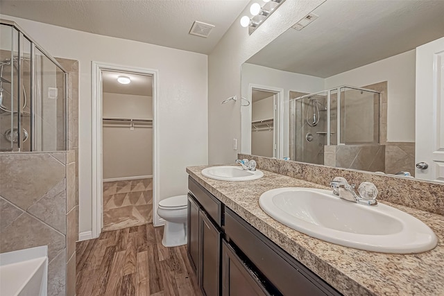 bathroom featuring a stall shower, visible vents, a sink, and wood finished floors