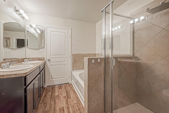 full bath featuring wood finished floors, a stall shower, a sink, and a bath