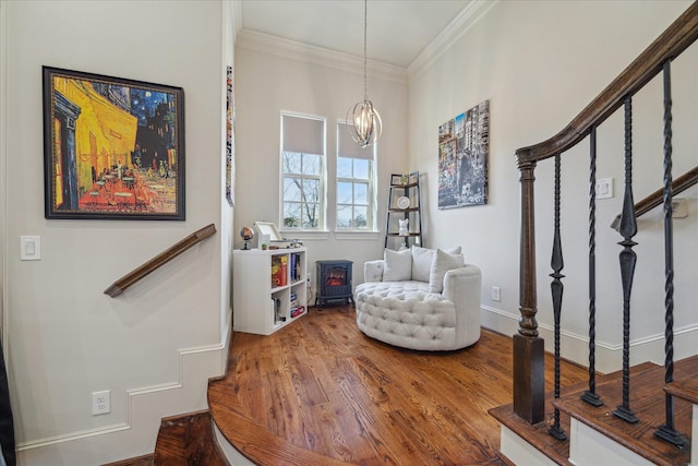 living area featuring stairs, a notable chandelier, ornamental molding, and wood finished floors