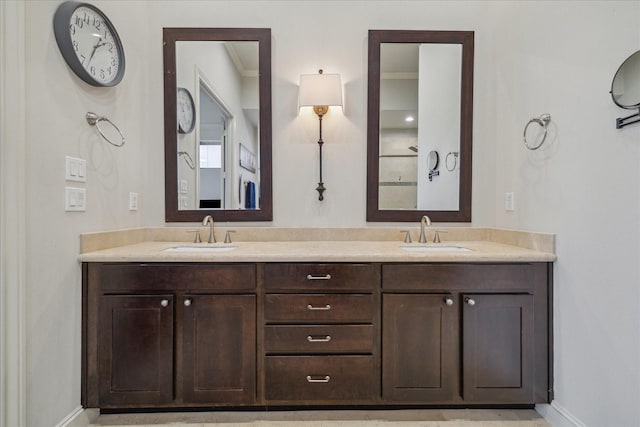 bathroom with crown molding, double vanity, a sink, and baseboards