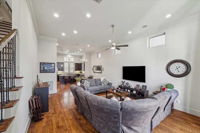 living room featuring ornamental molding, visible vents, stairway, and wood finished floors