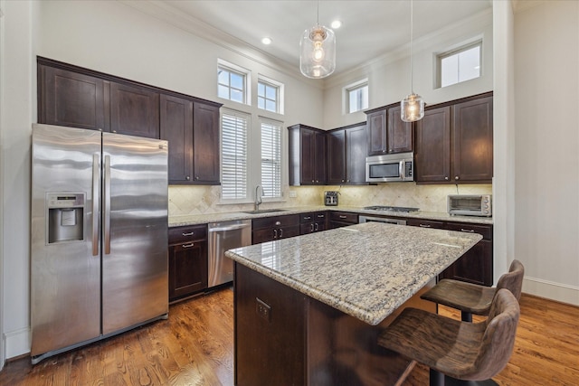 kitchen featuring stainless steel appliances, dark wood-type flooring, a sink, dark brown cabinets, and crown molding