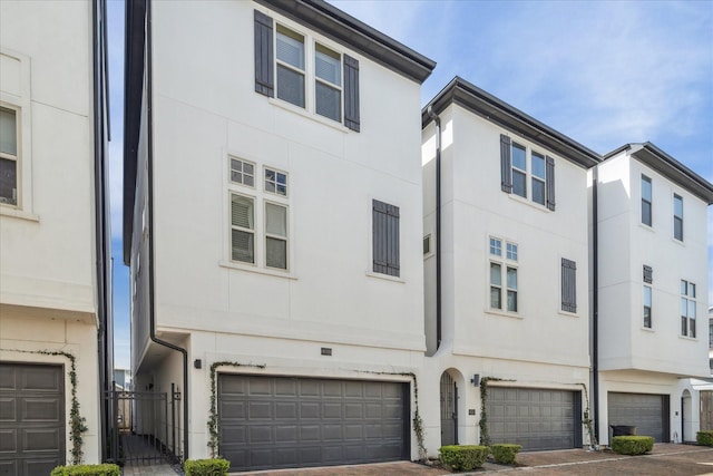 view of property featuring an attached garage, decorative driveway, and stucco siding