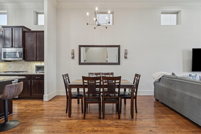 dining space featuring a chandelier, crown molding, baseboards, and wood finished floors