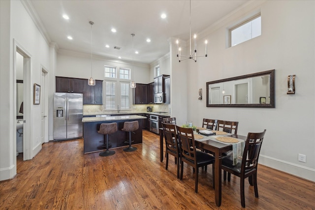 dining space featuring visible vents, baseboards, dark wood finished floors, a high ceiling, and crown molding