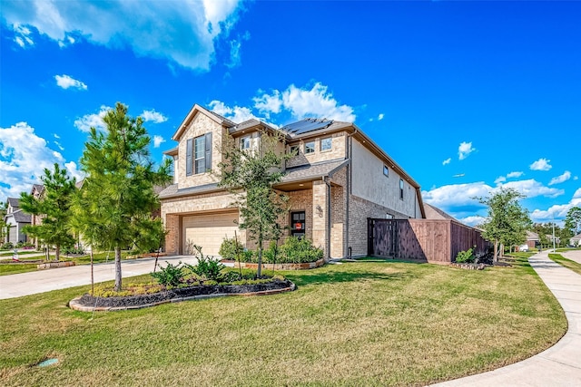 traditional-style home with a garage, solar panels, brick siding, driveway, and a front yard