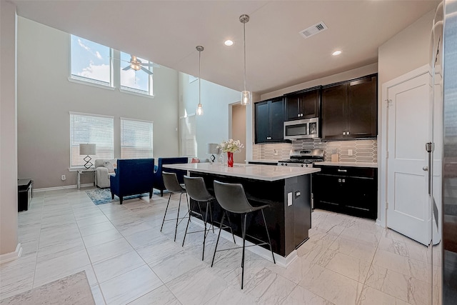 kitchen featuring marble finish floor, stainless steel appliances, light countertops, visible vents, and backsplash