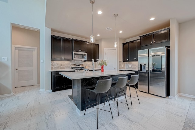 kitchen featuring marble finish floor, light countertops, visible vents, appliances with stainless steel finishes, and a kitchen breakfast bar