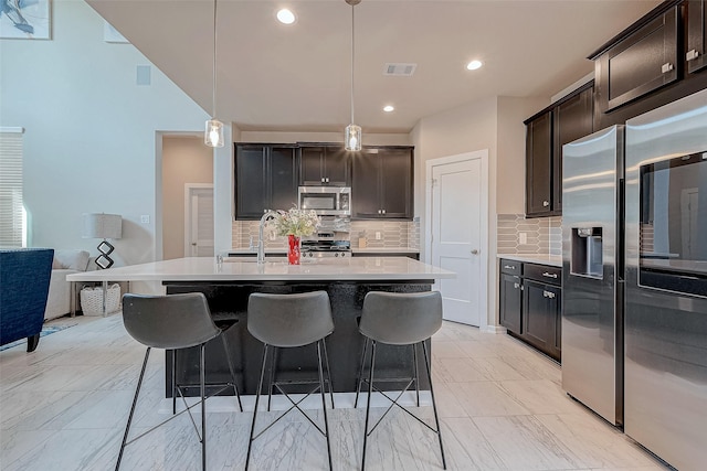 kitchen with visible vents, marble finish floor, stainless steel appliances, a kitchen bar, and a sink