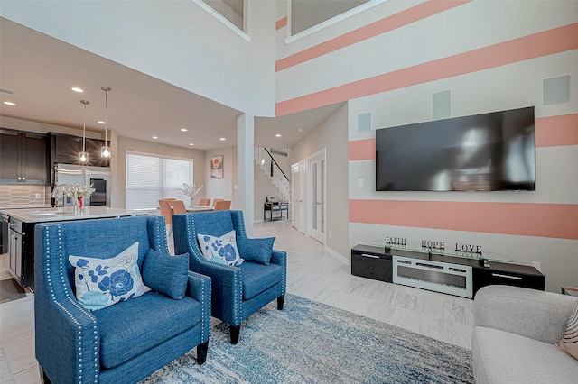 living area with recessed lighting, a towering ceiling, baseboards, stairs, and marble finish floor