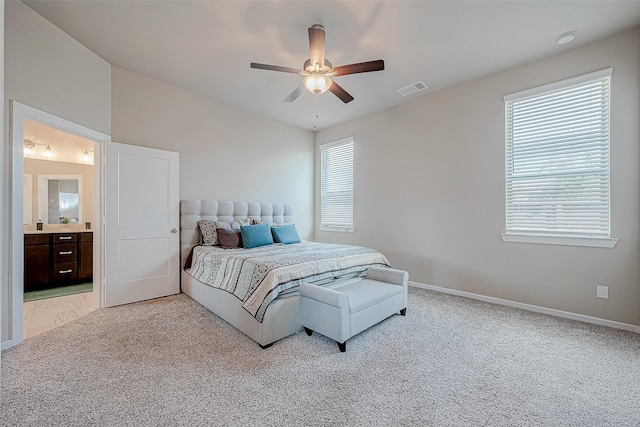 bedroom featuring light colored carpet, visible vents, ensuite bath, and baseboards