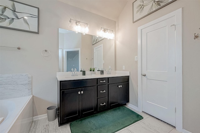 bathroom with double vanity, marble finish floor, a tub, and a sink