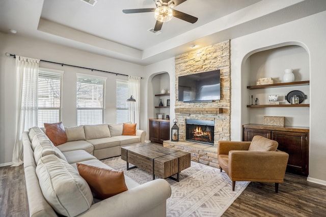 living area featuring built in features, a raised ceiling, dark wood finished floors, and baseboards