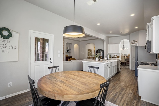 dining area featuring arched walkways, recessed lighting, visible vents, dark wood-type flooring, and baseboards