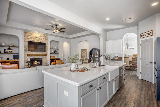 kitchen featuring dark wood finished floors, visible vents, open floor plan, a sink, and a stone fireplace