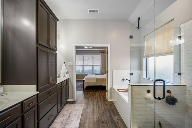 ensuite bathroom with a garden tub, double vanity, visible vents, a shower stall, and wood finished floors