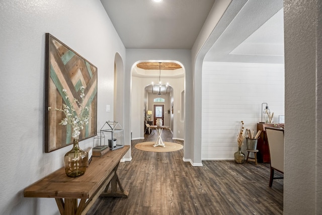 interior space with arched walkways, baseboards, and wood finished floors