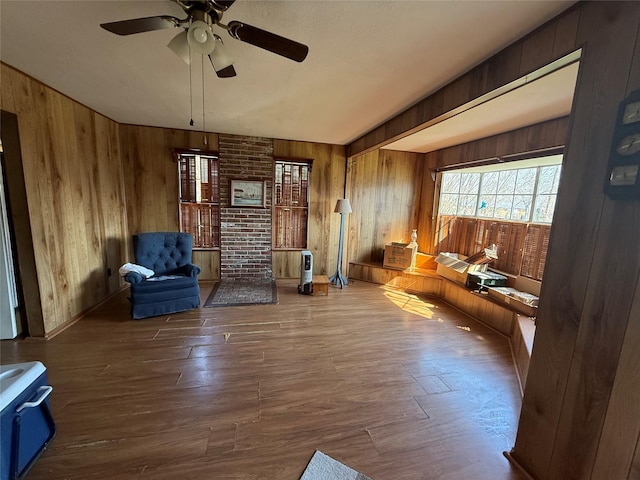 unfurnished room with wooden walls, a ceiling fan, and wood finished floors