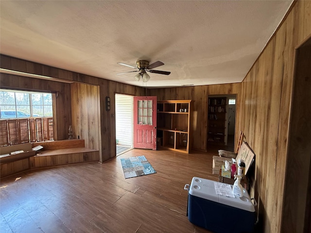 unfurnished living room featuring a textured ceiling, wood finished floors, and wooden walls