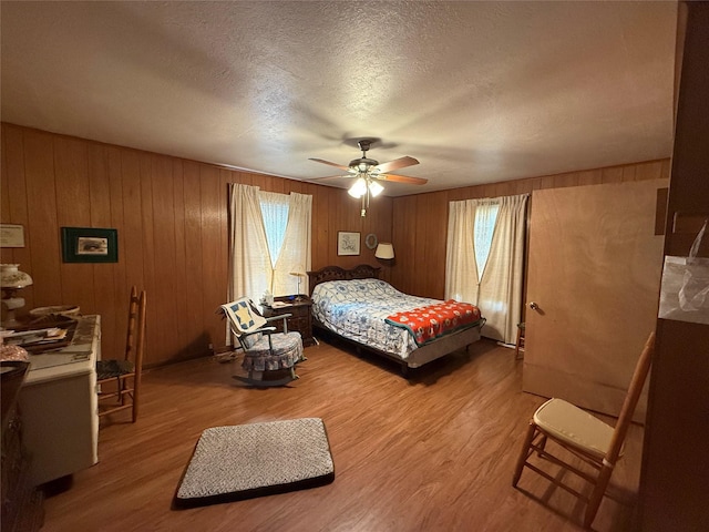 bedroom with a textured ceiling, multiple windows, and wood finished floors