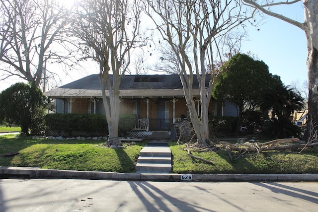 ranch-style home featuring covered porch and a front yard