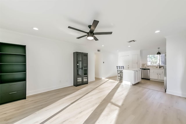 unfurnished living room with recessed lighting, visible vents, light wood-style flooring, a sink, and baseboards