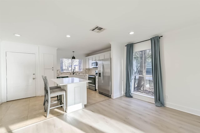 kitchen with plenty of natural light, visible vents, appliances with stainless steel finishes, and decorative backsplash