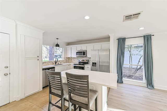 kitchen featuring tasteful backsplash, light countertops, visible vents, appliances with stainless steel finishes, and white cabinetry