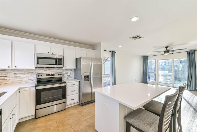 kitchen with appliances with stainless steel finishes, visible vents, a kitchen island, and decorative backsplash