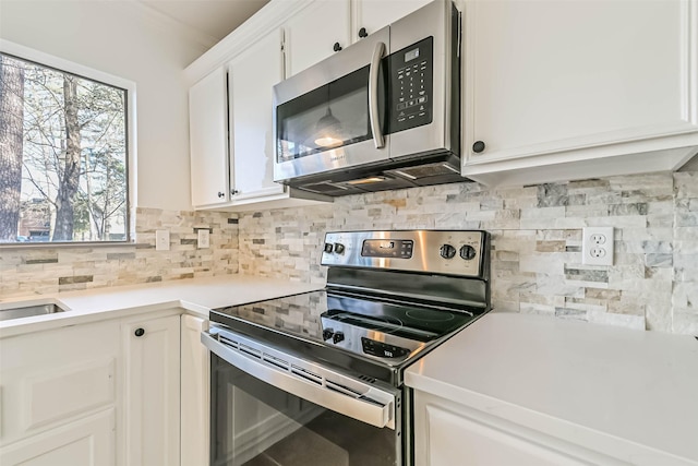 kitchen with tasteful backsplash, appliances with stainless steel finishes, white cabinets, and light countertops