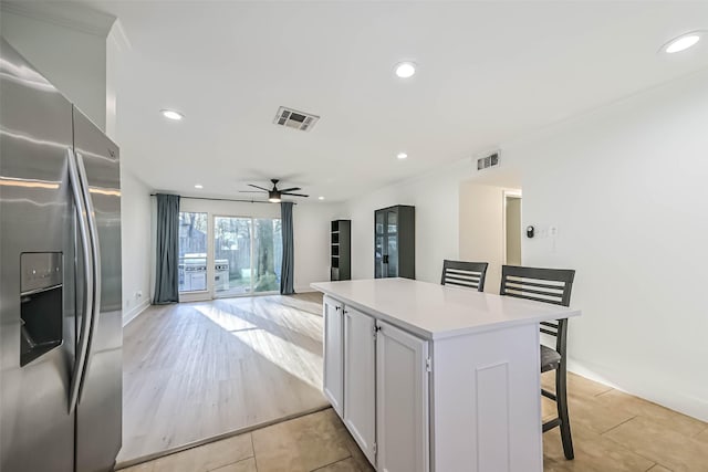 kitchen featuring stainless steel refrigerator with ice dispenser, recessed lighting, visible vents, a kitchen island, and a kitchen breakfast bar