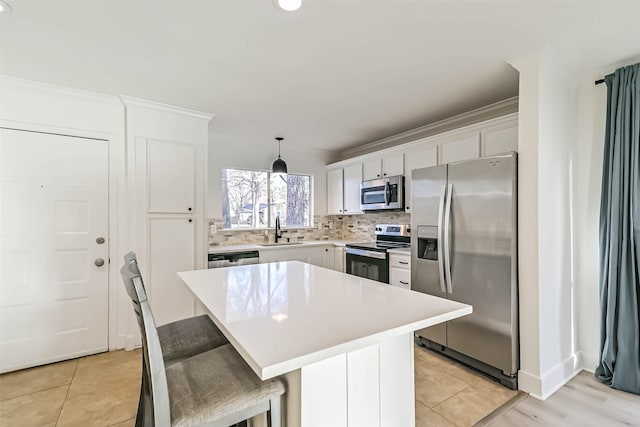 kitchen featuring stainless steel appliances, a sink, white cabinets, light countertops, and tasteful backsplash