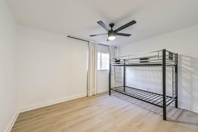 unfurnished bedroom featuring a ceiling fan, baseboards, and light wood finished floors