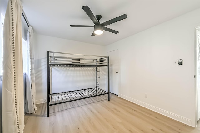 unfurnished bedroom with ceiling fan, wood finished floors, and baseboards