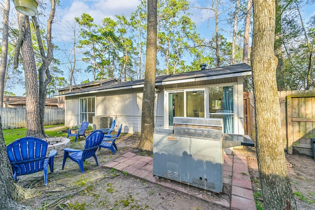 back of house featuring an outdoor fire pit and fence