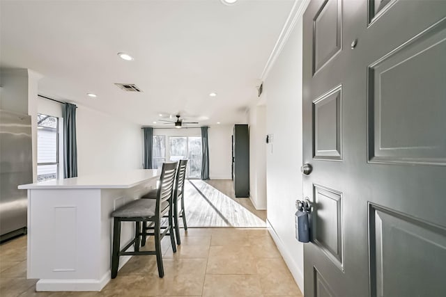 kitchen with a healthy amount of sunlight, light tile patterned flooring, stainless steel refrigerator, and a kitchen breakfast bar