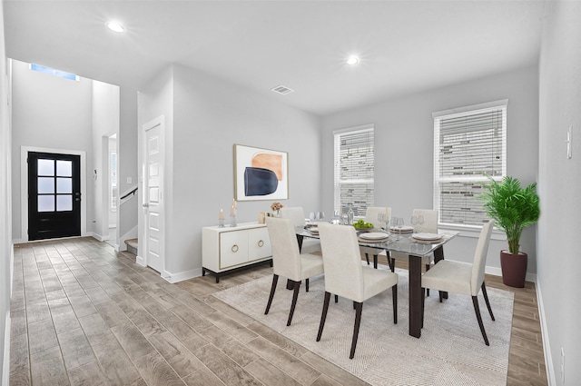 dining space with light wood-style flooring, recessed lighting, visible vents, baseboards, and stairs