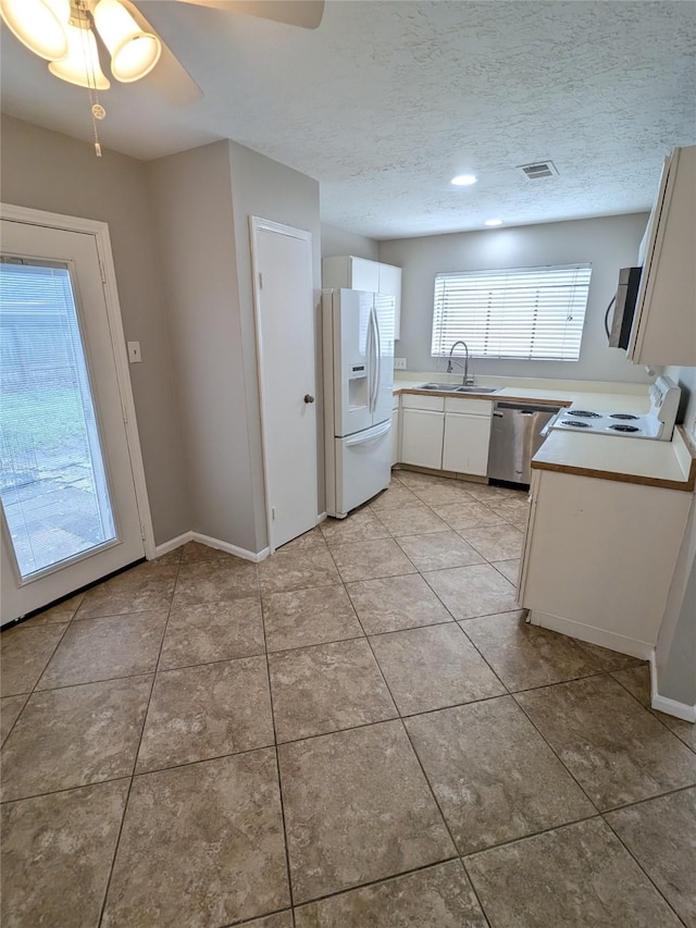 kitchen with stainless steel appliances, light countertops, white cabinets, a sink, and a textured ceiling