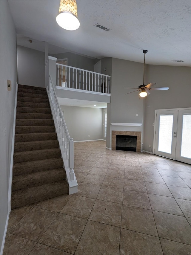 unfurnished living room featuring a fireplace, visible vents, baseboards, a ceiling fan, and stairway