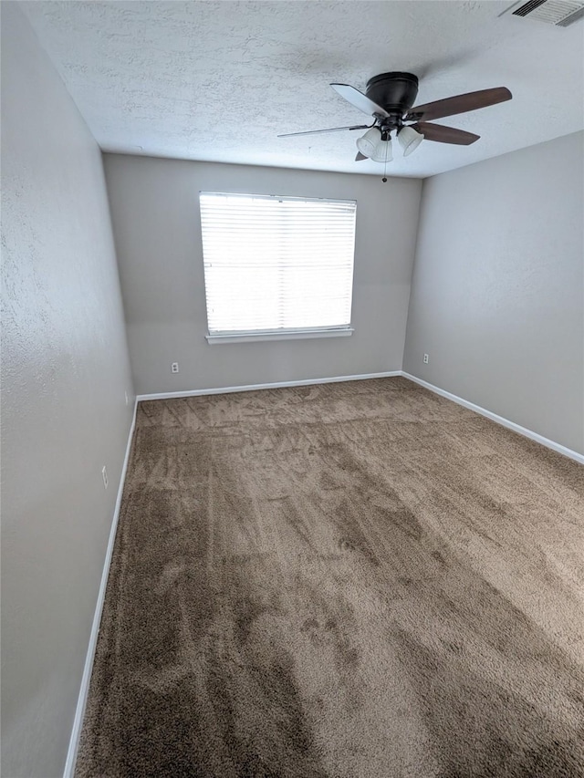 carpeted empty room featuring a ceiling fan, visible vents, a textured ceiling, and baseboards