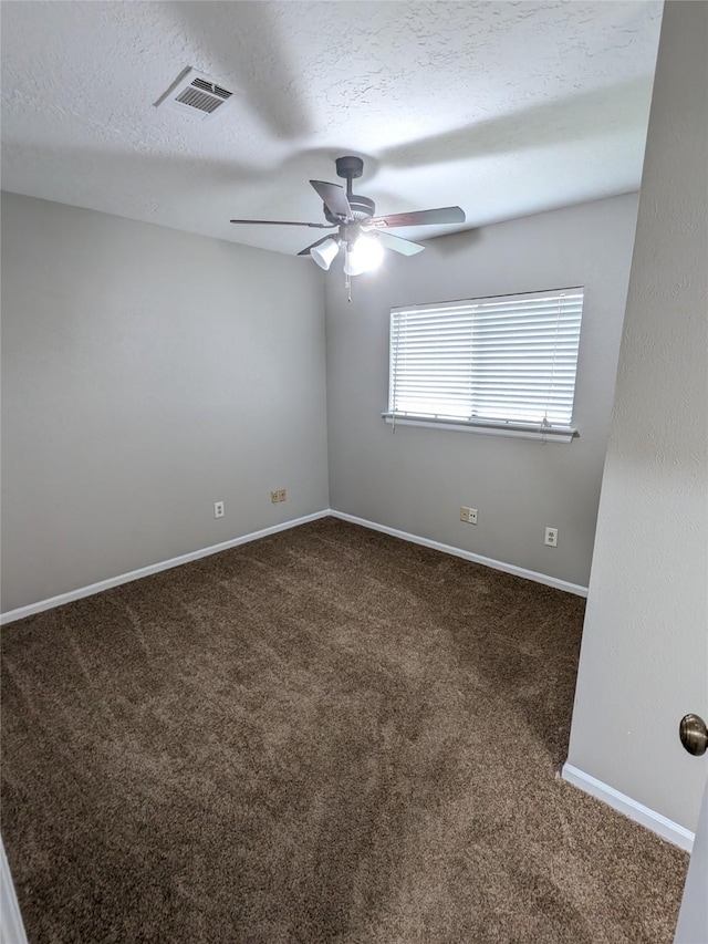 unfurnished room with baseboards, visible vents, a ceiling fan, a textured ceiling, and dark carpet