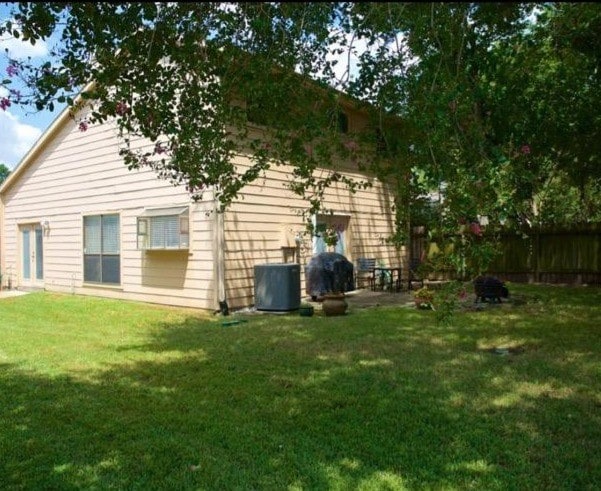 rear view of house featuring a patio area, central AC, a lawn, and fence