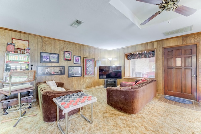 carpeted living area featuring crown molding, visible vents, and a ceiling fan