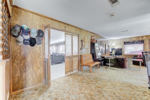 carpeted home office with wooden walls, visible vents, and crown molding