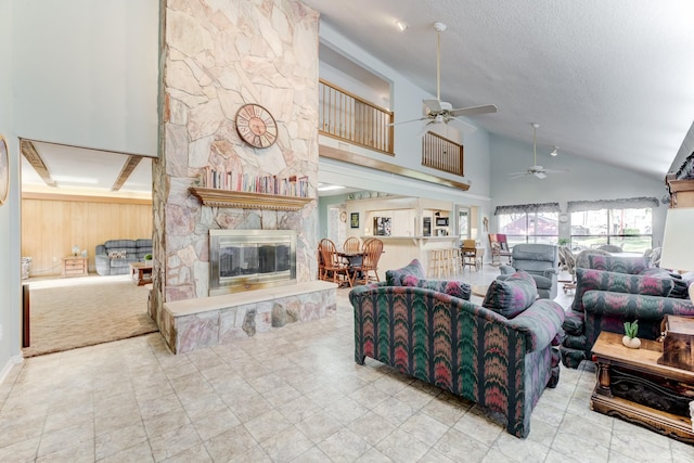 living area featuring wood walls, a fireplace, high vaulted ceiling, and a textured ceiling