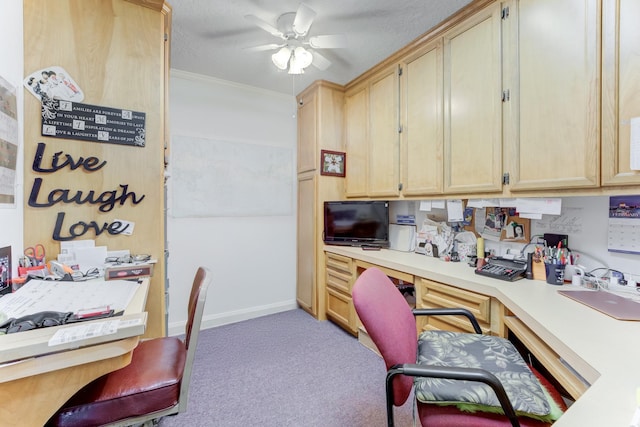 carpeted home office featuring crown molding, baseboards, a ceiling fan, and built in study area