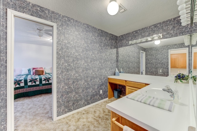 bathroom with wallpapered walls, baseboards, connected bathroom, a textured ceiling, and vanity