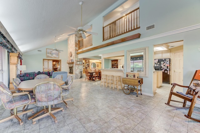 dining space with a textured ceiling, high vaulted ceiling, visible vents, baseboards, and a ceiling fan