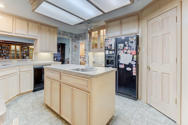 kitchen with light countertops, light brown cabinets, a sink, a kitchen island with sink, and black appliances